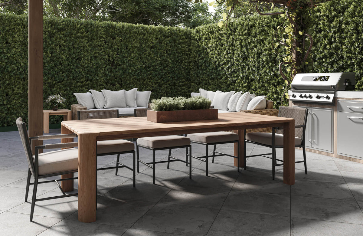 Modern outdoor dining patio with large format stone look tile flooring, wood table, cushioned seating, and sleek contemporary grill area.