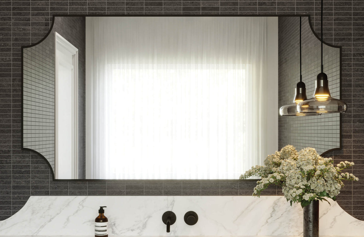 Sleek bathroom with a sculpted-edge rectangular mirror, white marble vanity, dark linear tiles, and black matte fixtures.
