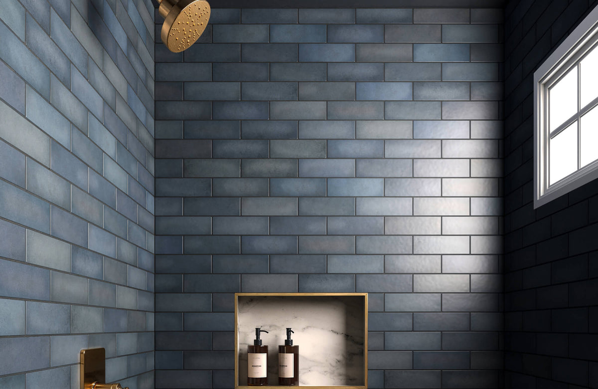 Sleek navy-blue subway tiles add depth to this modern bathroom, complemented by brass fixtures and a marble niche.