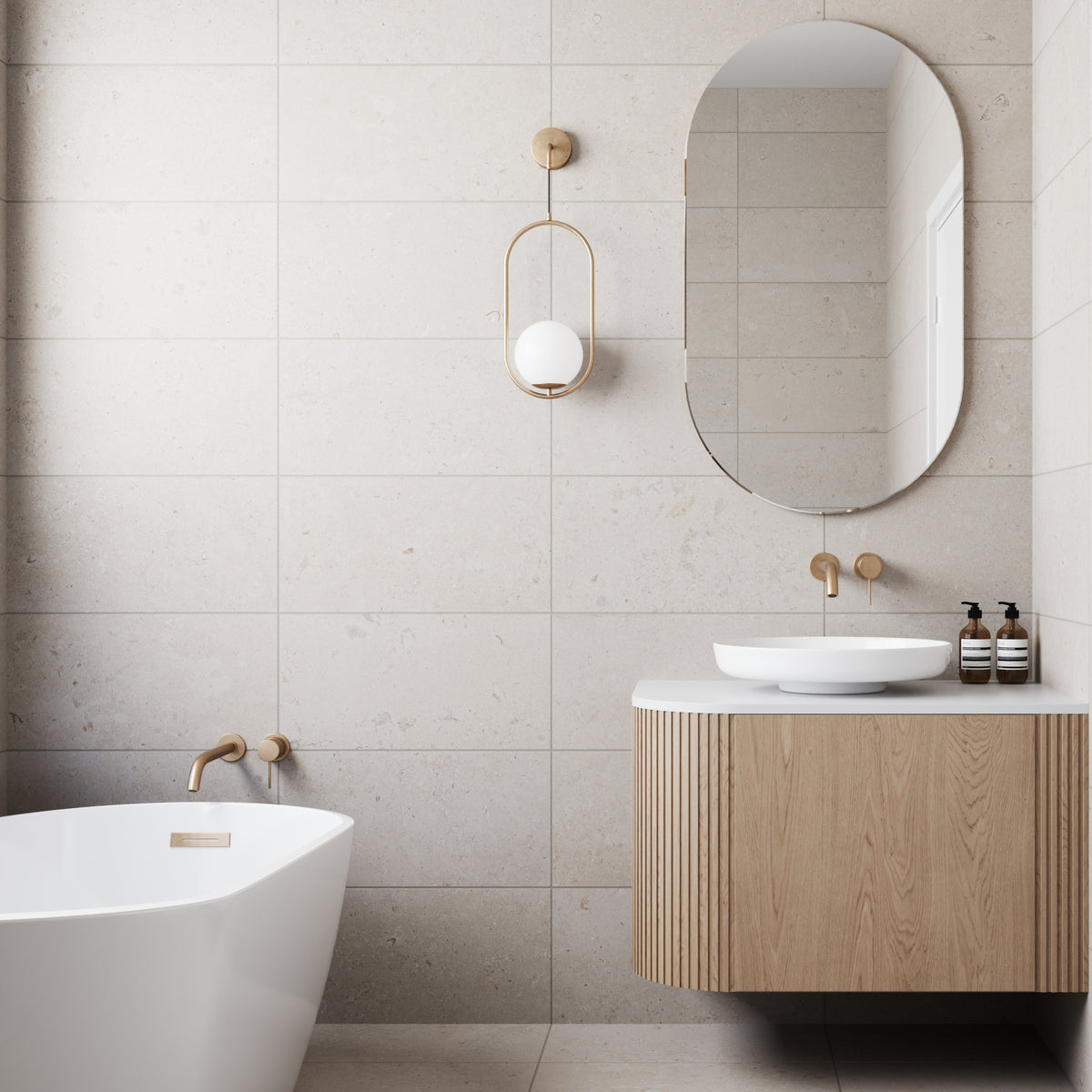 A modern bathroom exuding serene elegance, featuring walls and floors adorned with Wren 12x24 Matte Porcelain Tile in Dune. This limestone-look tile infuses the space with a natural, tranquil ambiance, its subtle textures and warm tones echoing the distinctive beauty of authentic limestone. Every detail contributes to a sanctuary where contemporary design meets timeless, organic allure.