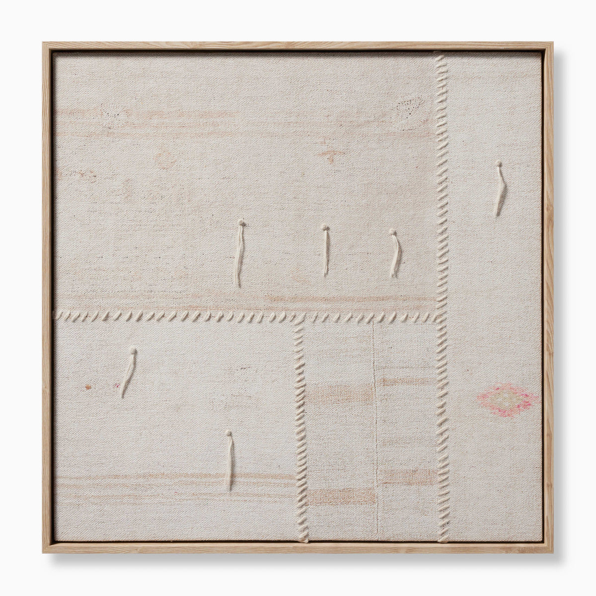 Square framed textile artwork with visible stitching, natural woven texture, and subtle hints of blush and rust on a neutral background.