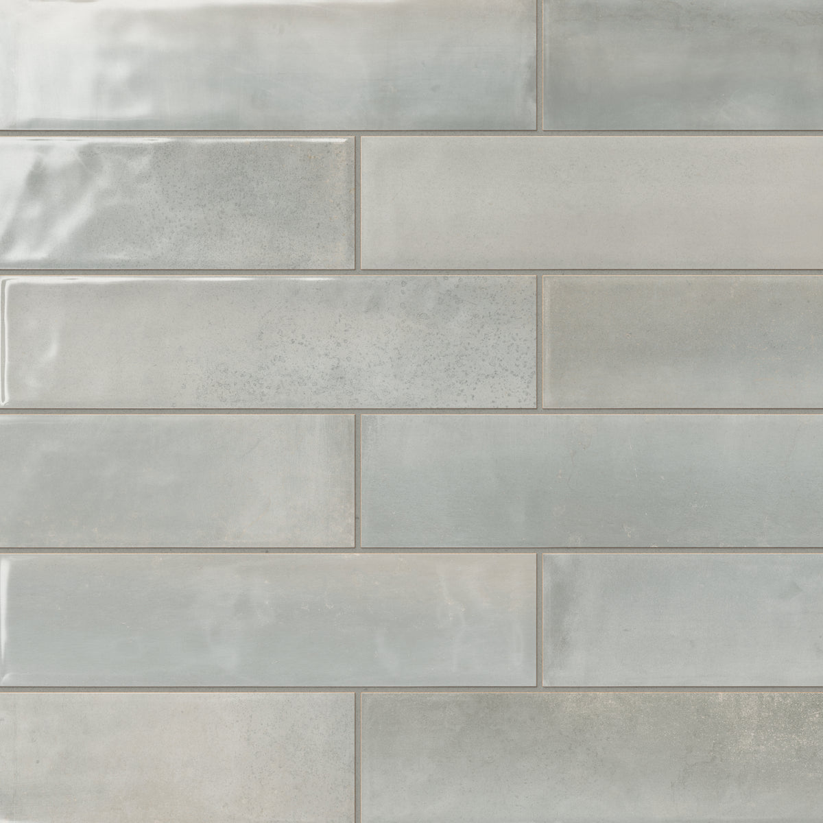 Light grey glossy subway tiles with subtle tonal variations, offering a sleek and versatile option for modern interior designs.