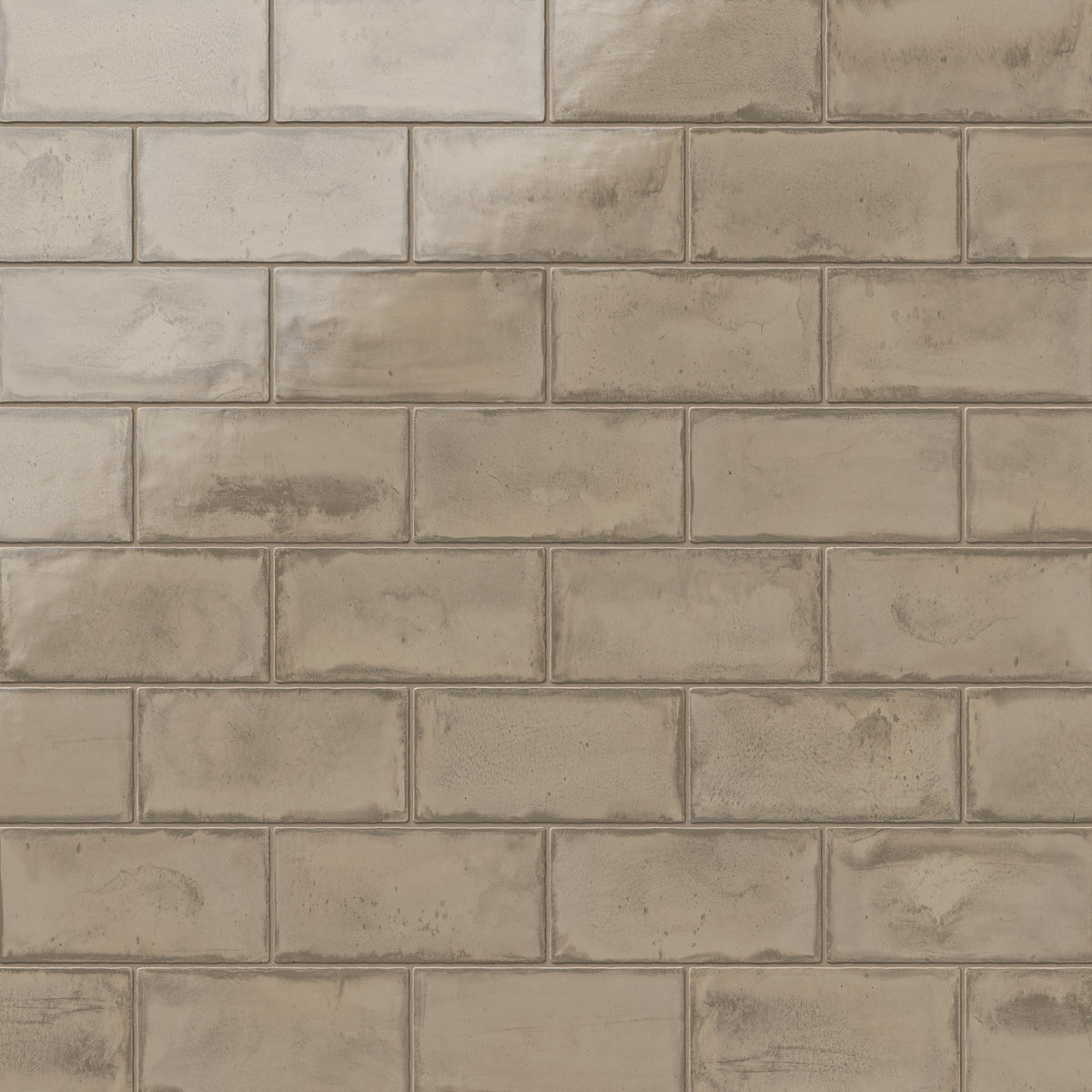 Glossy taupe ceramic subway tiles in a 3x6 format and subtle handcrafted texture, perfect for creating a natural, warm ambiance