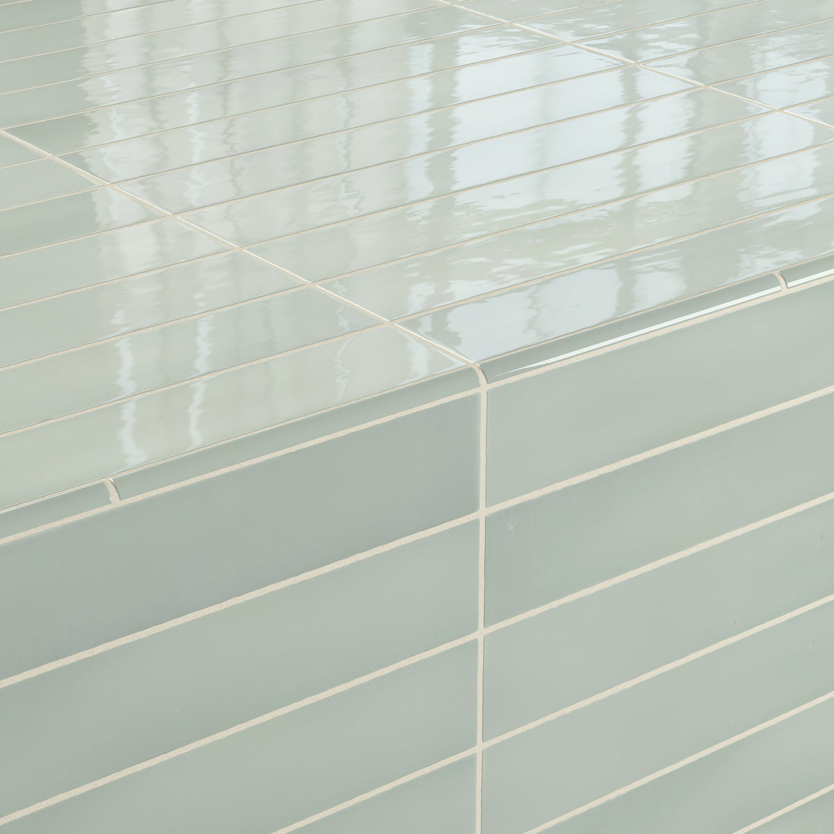 A corner detail showcasing glossy pistachio green quarter round tiles with smooth grout lines, reflecting soft light