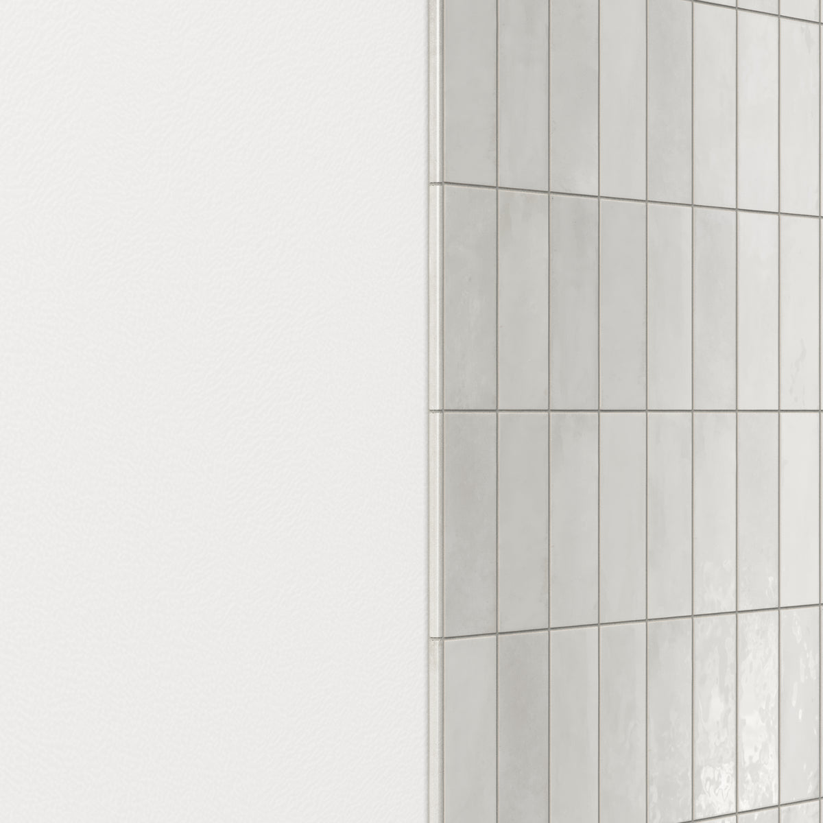 Wall finished with glossy ceramic subway tiles in shifting light gray tones, accented by a rounded tile edge trim for a smooth, polished transition