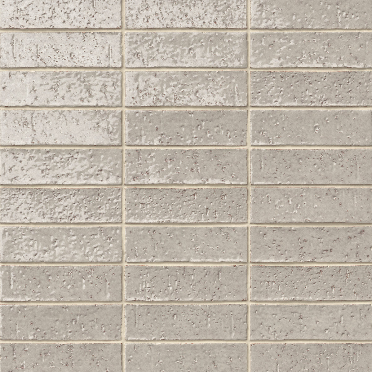 Handmade brick tiles with a gleaming grayish-beige glaze, subtle dimples, pinholes, and organic surface variation.