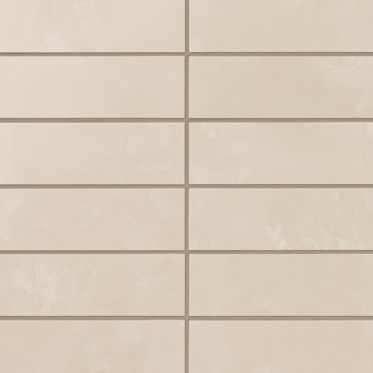 A run of 2x6 matte porcelain subway tiles reveals soft gray-beige shading, where earth-drawn variation and a powdery glaze add quiet depth to the surface.