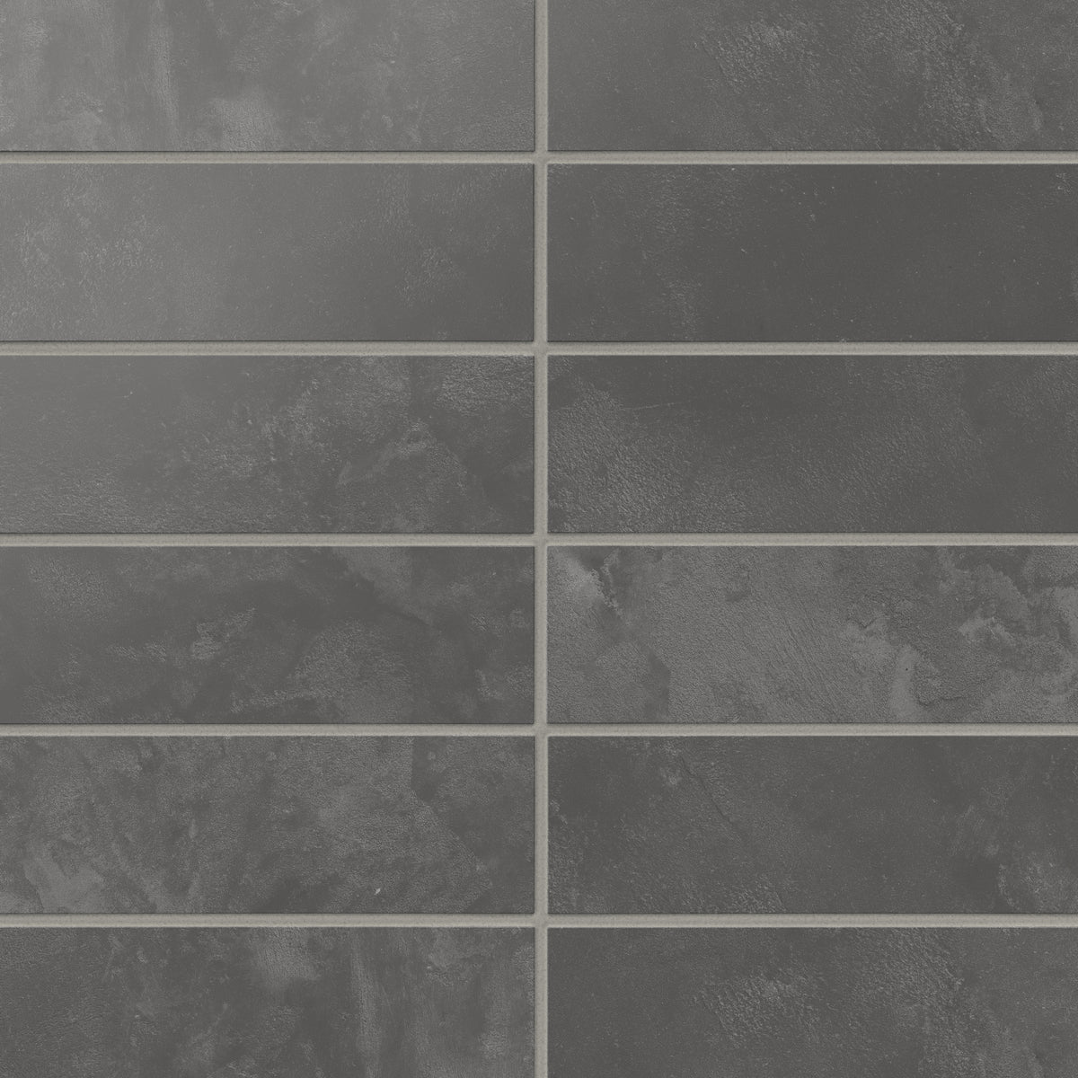 Dark gray 2x6 matte subway tiles show shifting, earth-drawn tones across the surface, laying out in a calm horizontal rhythm that suits kitchens and baths.