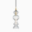 Elongated pendant with tiered, ribbed glass and aged brass accents, casting shimmering light through sculptural curves.