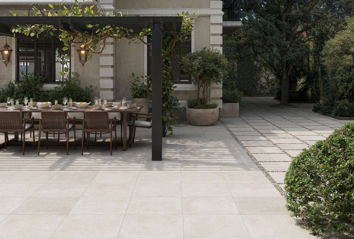 Sophisticated outdoor dining area featuring Bowden 24x24 Grip Porcelain Pavers in Oat, blending neutral tones with timeless elegance.