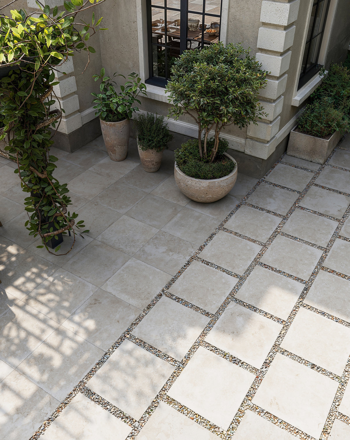 Charming patio design featuring Bowden 24x24 Grip Porcelain Pavers in Oat, paired with gravel joints for a sophisticated look.