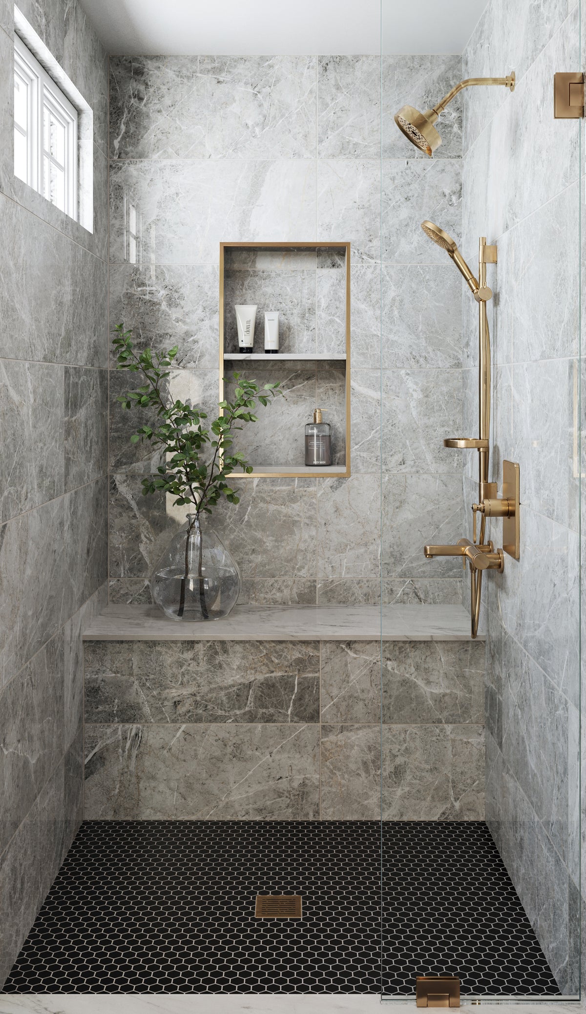 A luxurious shower space with polished grey veined wall tiles, gold fixtures, a built-in niche, and a contrasting black hexagon tile floor.