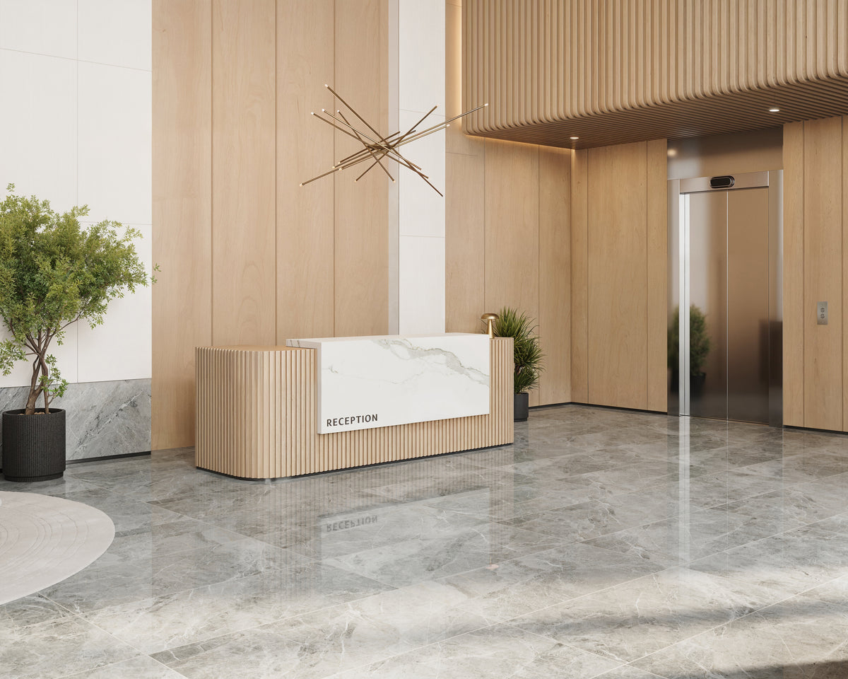 Polished tiles with soft grey veining reflect light beautifully in a modern reception, featuring warm wood panels and a sleek elevator.