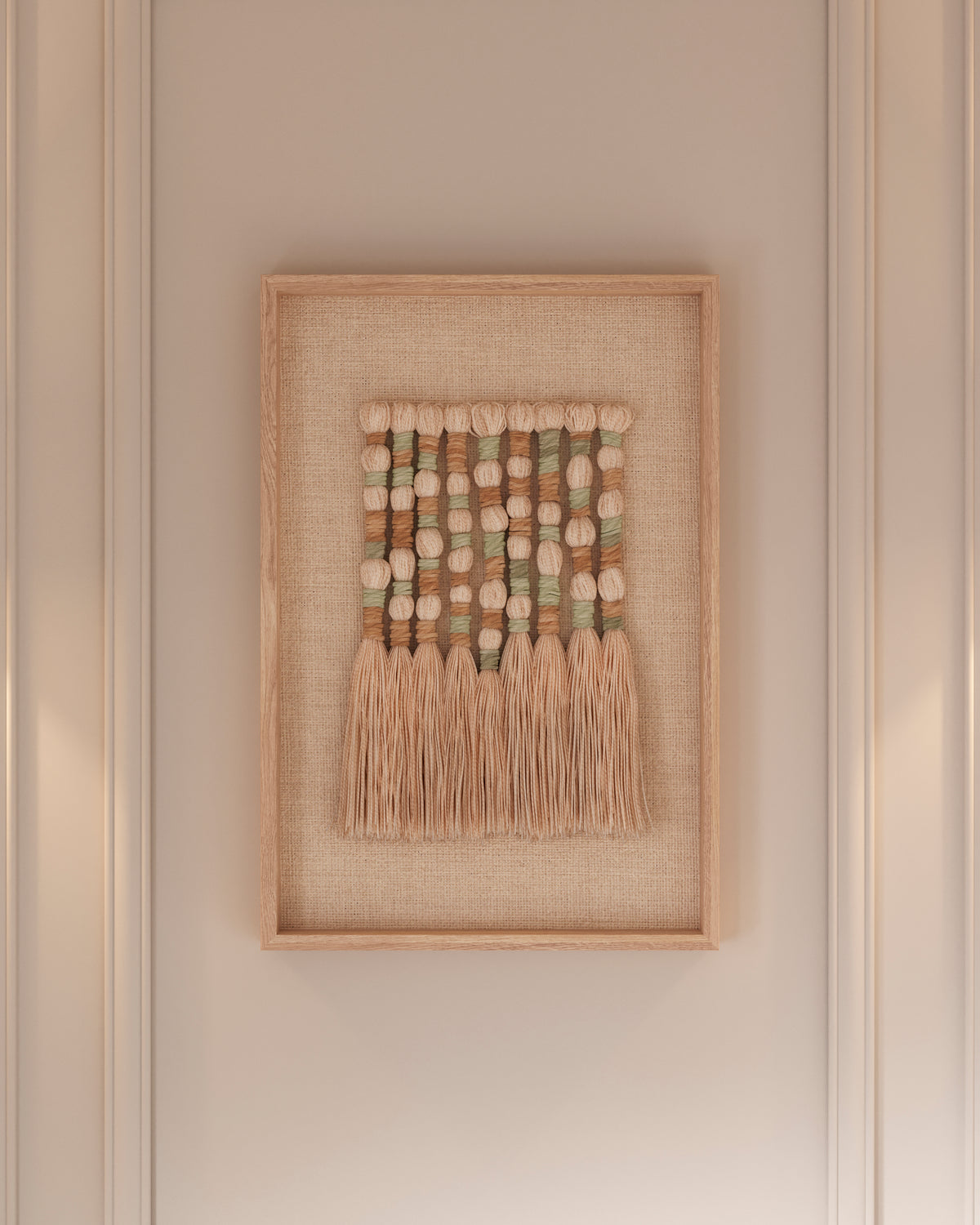 Framed textile wall art composed of hand-knotted wool and jute arranged in vertical rows, featuring rounded woven segments in soft cream, beige, and muted green tones, finished with long natural fringes that add texture and a relaxed, organic feel against a neutral backdrop.