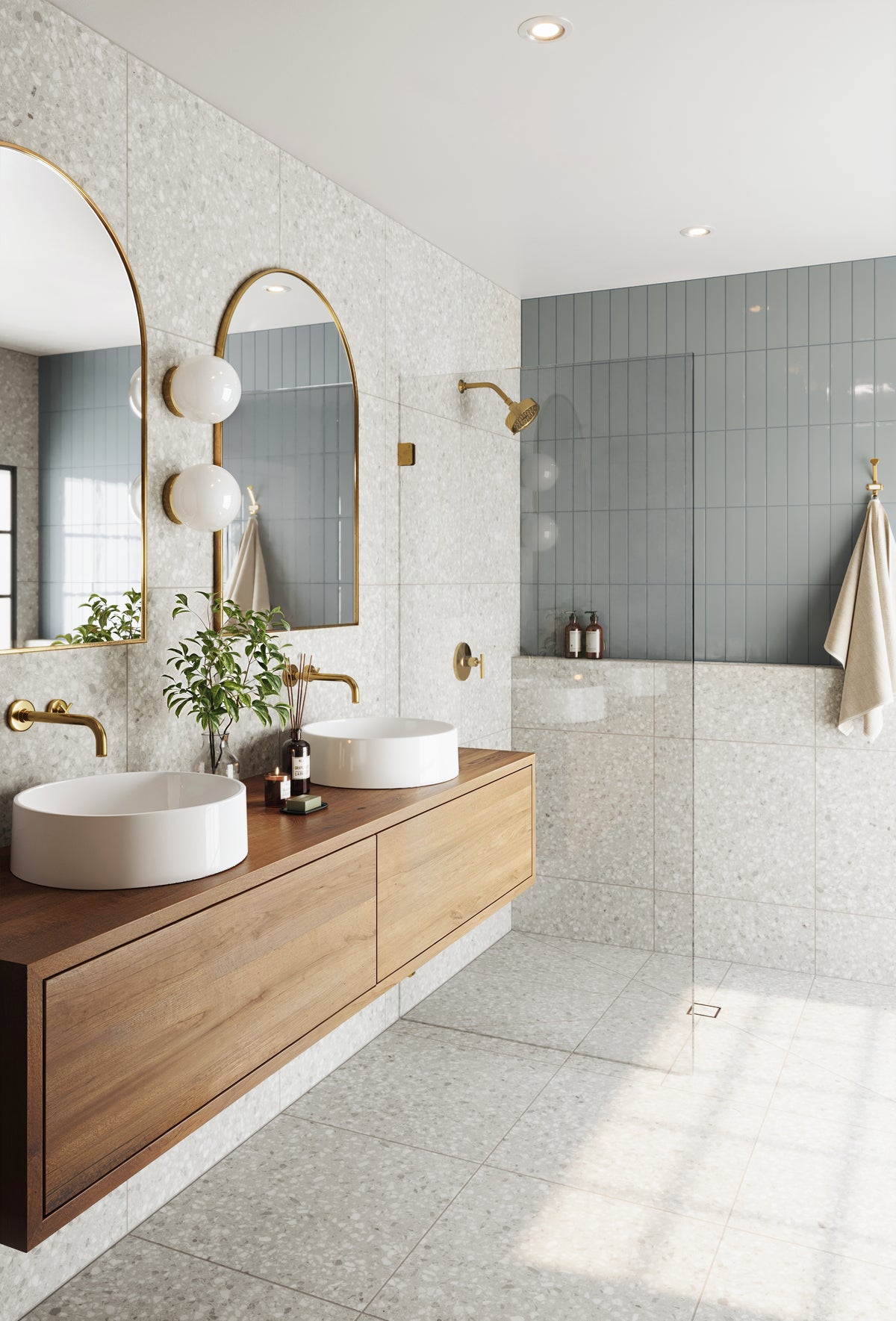 Modern bathroom design featuring eucalyptus green tiles as a shower accent wall, terrazzo flooring, and a wooden vanity with brass fixtures.