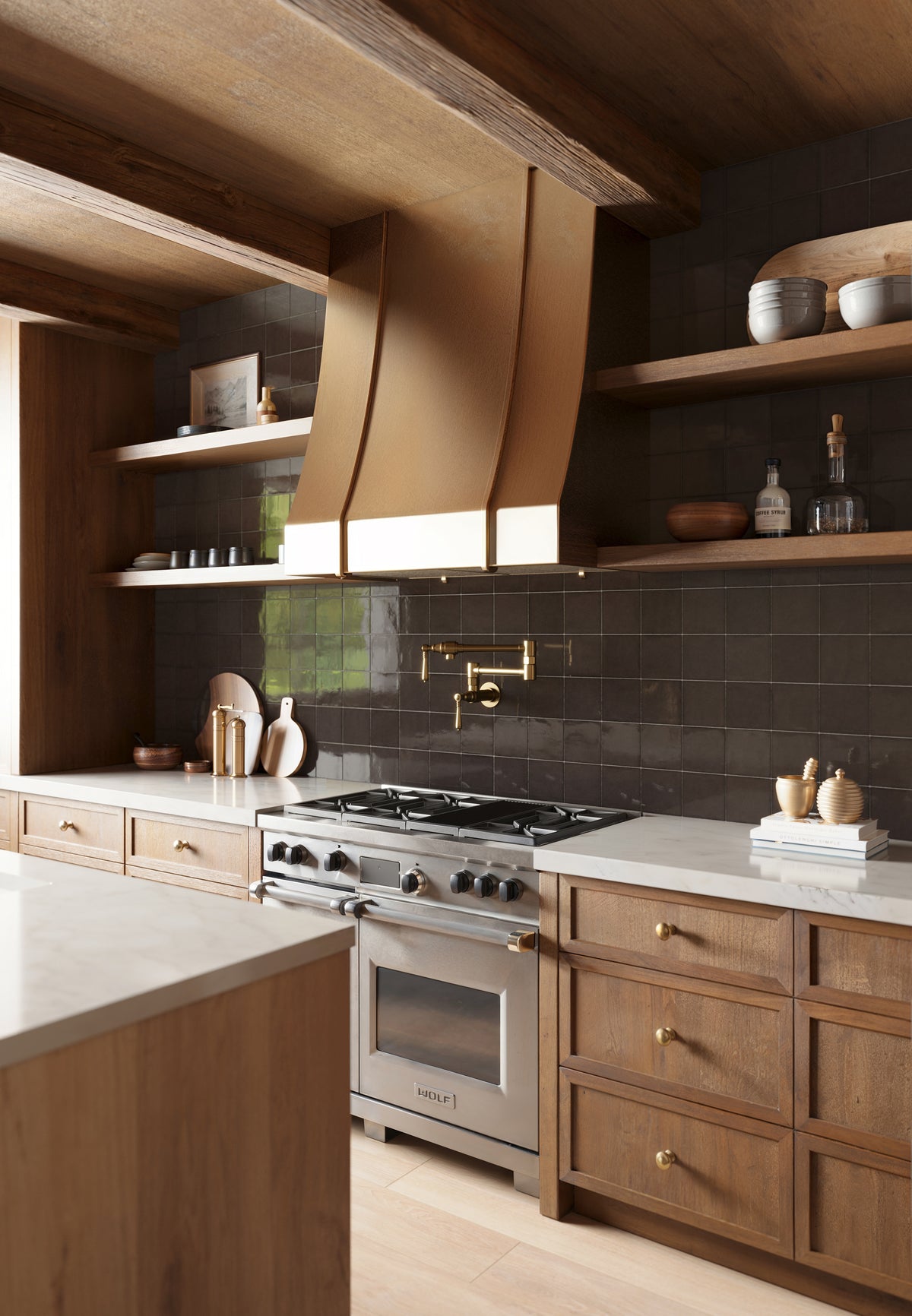 Rustic-modern kitchen featuring rich wood cabinetry, a brass range hood, marble countertops, and Camel-toned Jameson matte porcelain tile flooring.