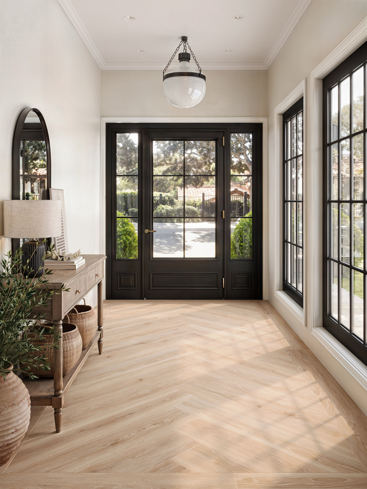 Bright and welcoming entryway featuring Jameson 8x48 matte porcelain tile in Camel, arranged in an elegant herringbone pattern to enhance its warm, natural wood-look design.