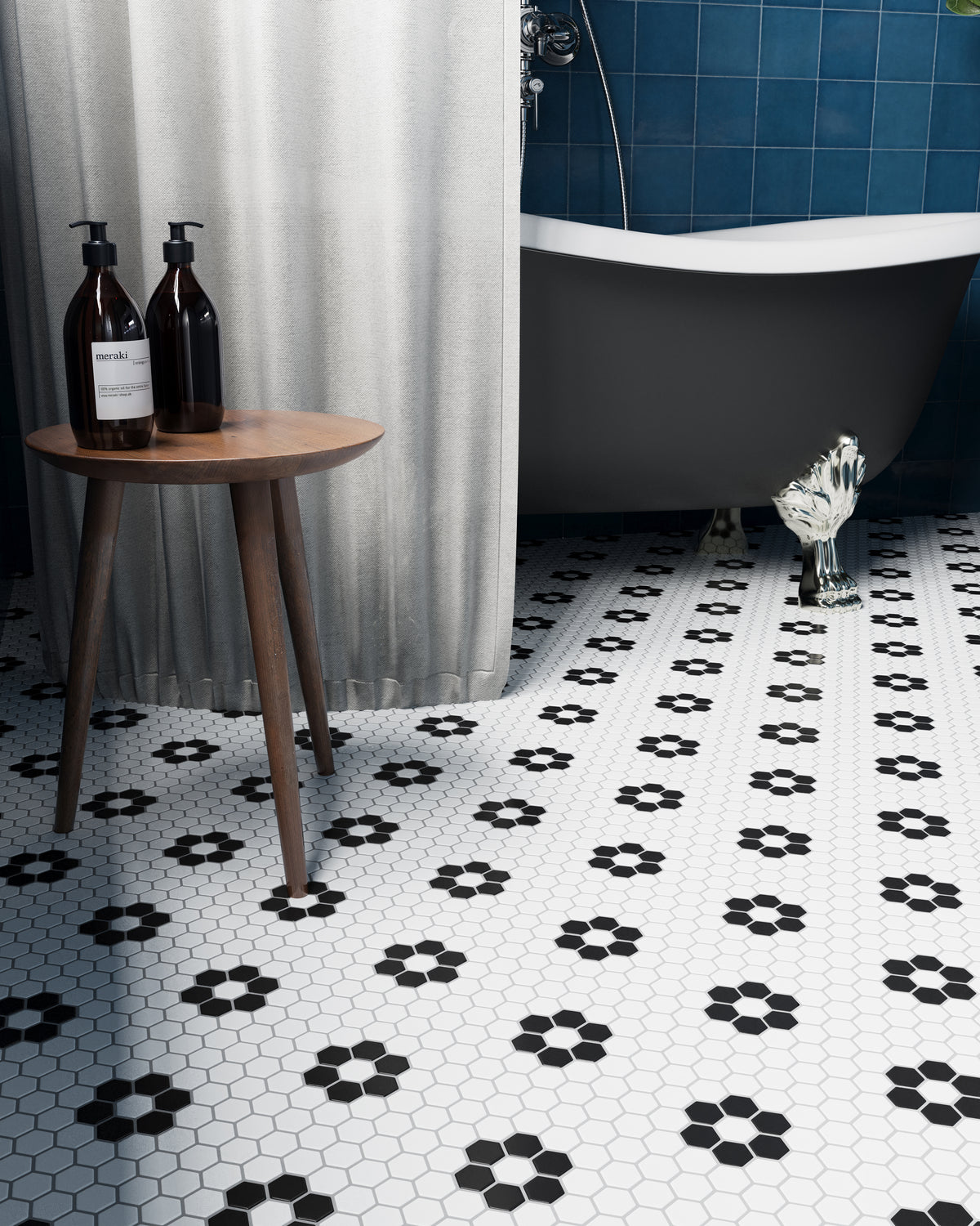 Close-up of a bathroom featuring a black and white flower hexagon mosaic floor, paired with a vintage clawfoot tub and wood side table.