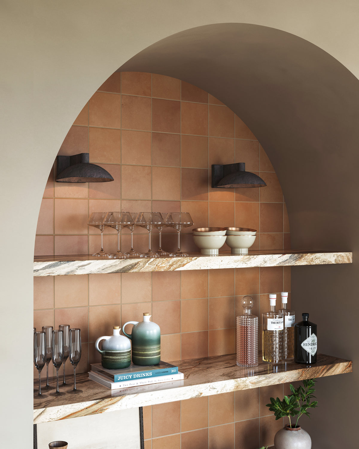 Arched niche with warm terracotta tile, marble shelves, black dome sconces, and neatly styled glassware and bar accessories