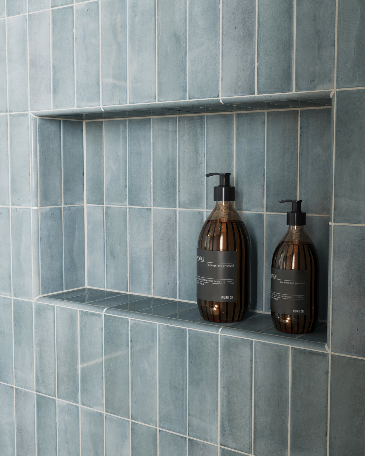 The blue glossy tiles form a sleek niche, adding texture and depth with subtle color variation, perfect for elegant bathroom storage.
