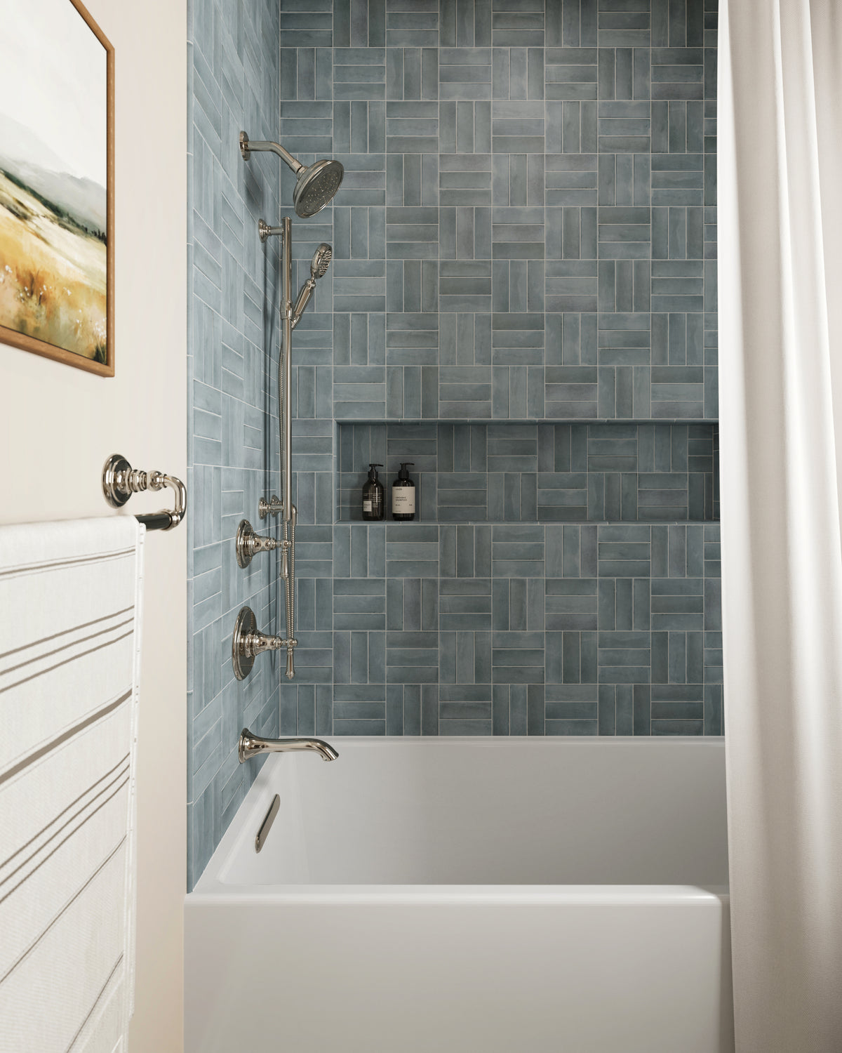 Modern bathtub alcove tiled in Natasha 2x6 matte porcelain in Ice, laid in a basketweave pattern with muted blue and gray tones.