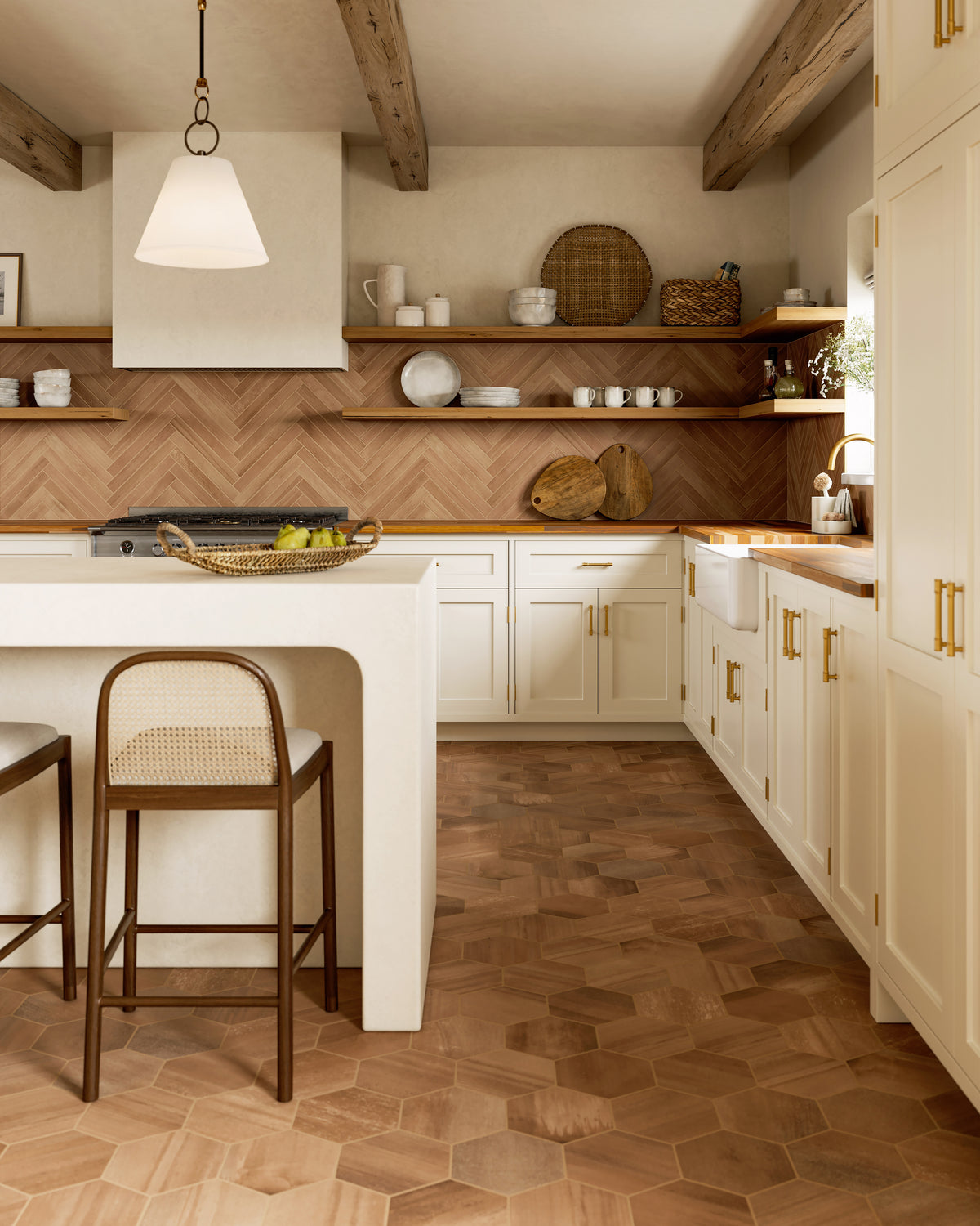 Warm kitchen with terracotta hexagon floor tiles and a matching herringbone backsplash, accented by cream cabinetry and wood beams.
