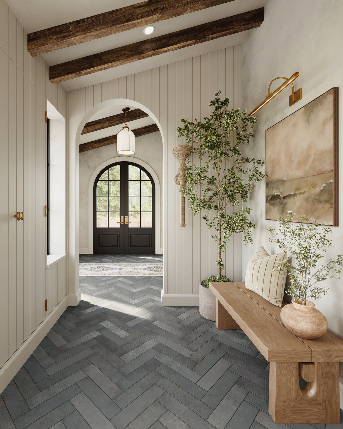 Bright entry hallway with herringbone tile floor, wood bench, woven rattan wall sconce, and arched doorway with natural light.