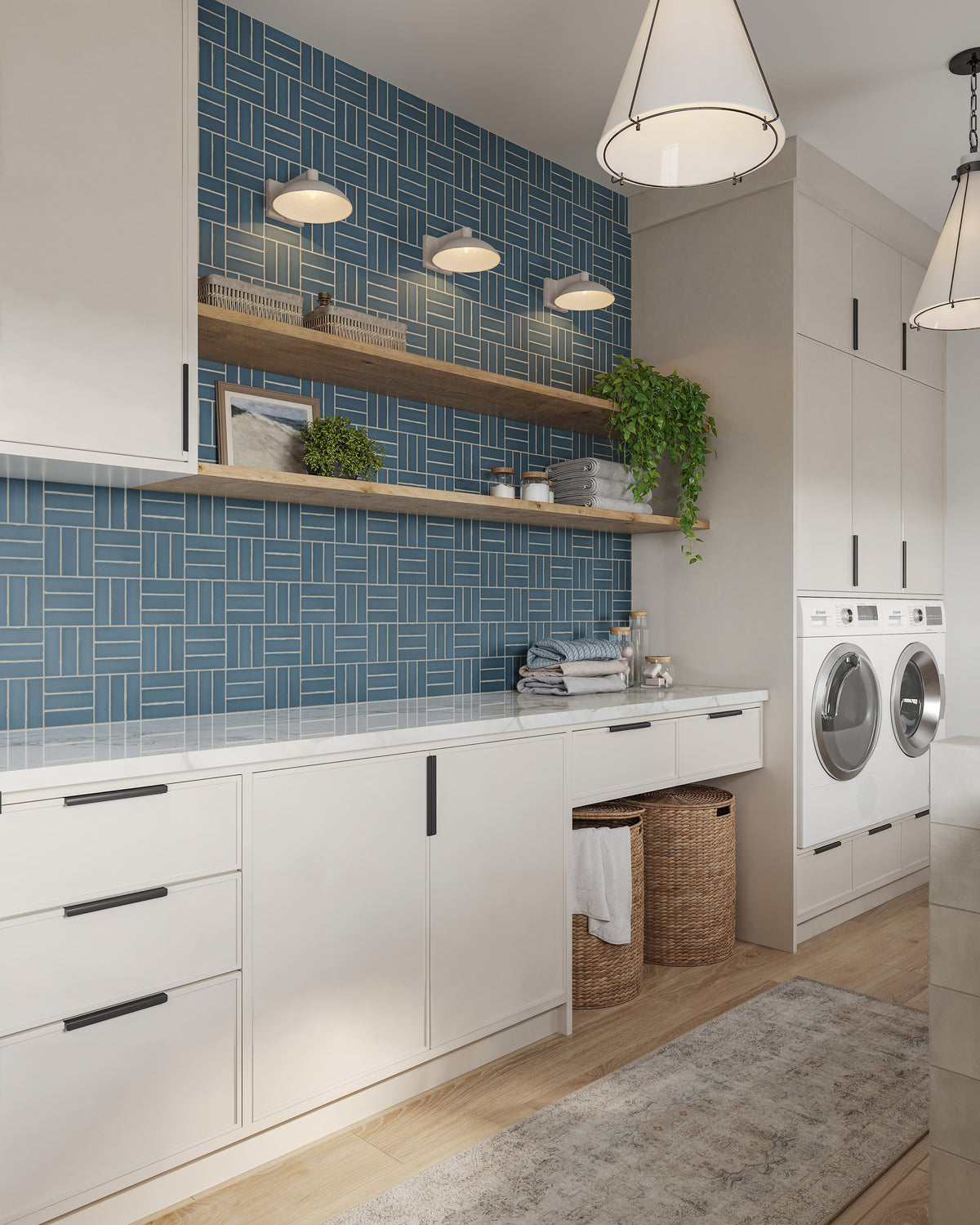 Bright laundry room with white cabinets, blue tile backsplash, open wood shelves, woven baskets, and three small dome wall sconces above the counter