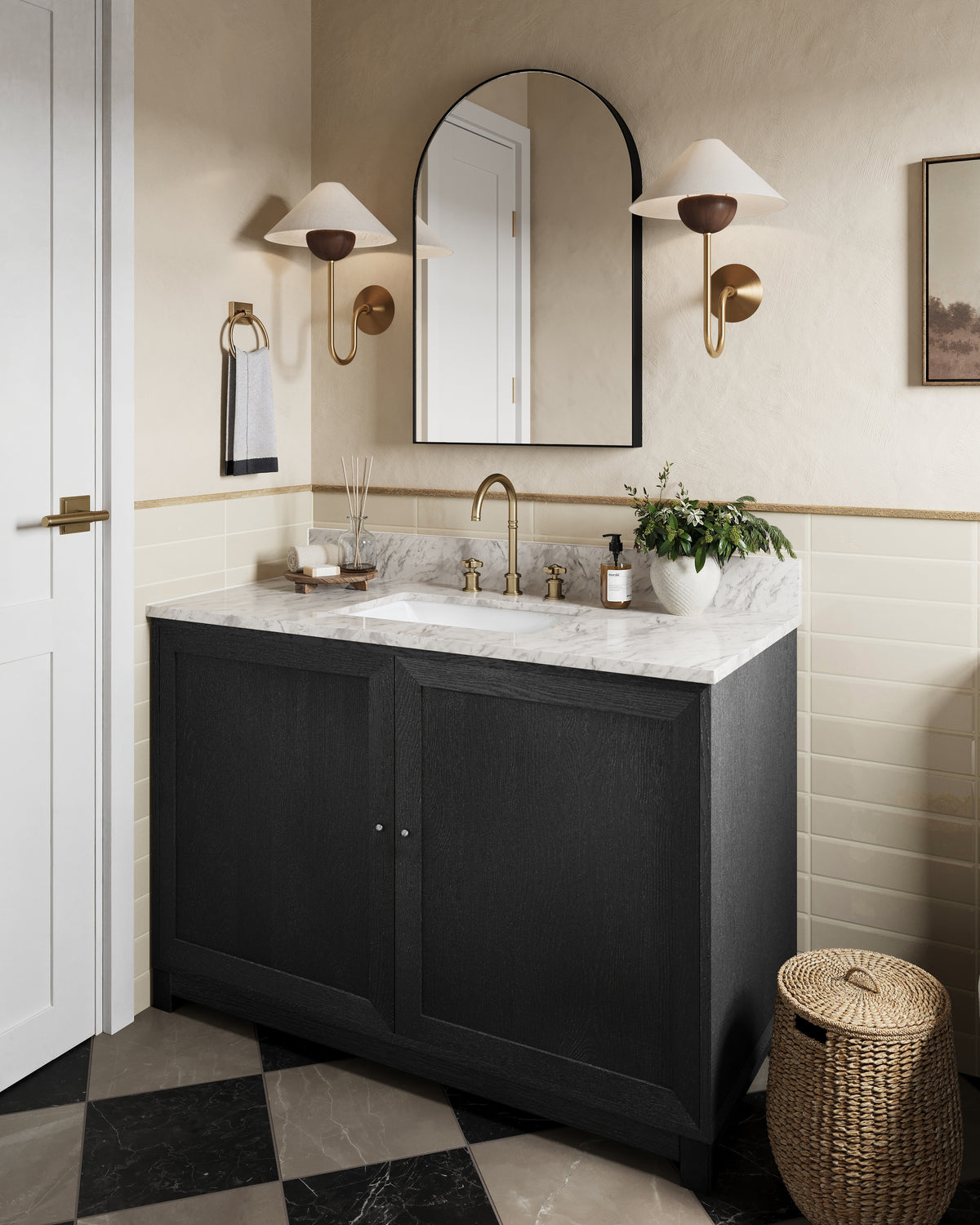 Bathroom vanity with marble top, black cabinet, oval mirror, and paired patina brass sconces with walnut detail and white linen shades