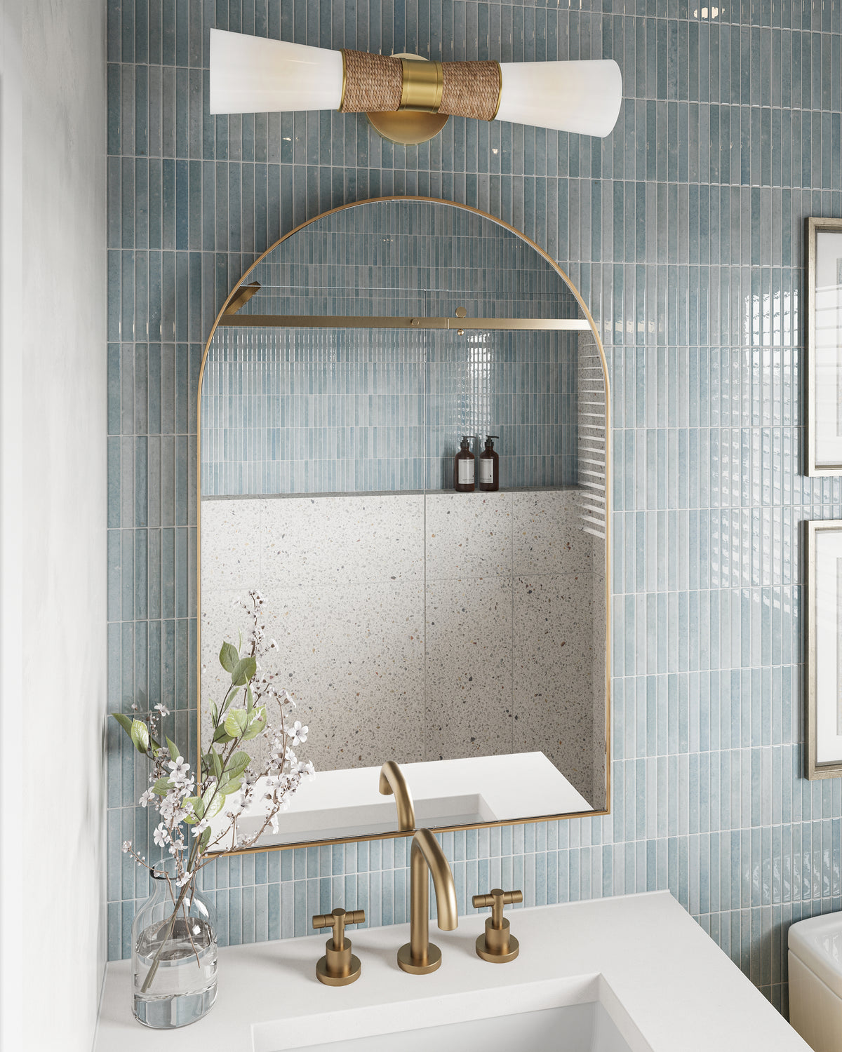 Bathroom vanity with brass faucet, arched mirror, blue vertical tile wall, and rattan accented wall sconce above sink.