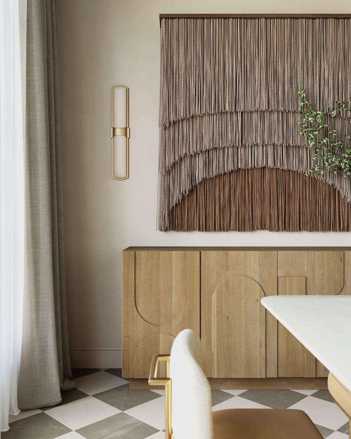 Aged brass wall sconce with a slim vertical frame and cylindrical alabaster diffuser mounted beside draped textile wall art in a modern dining space.
