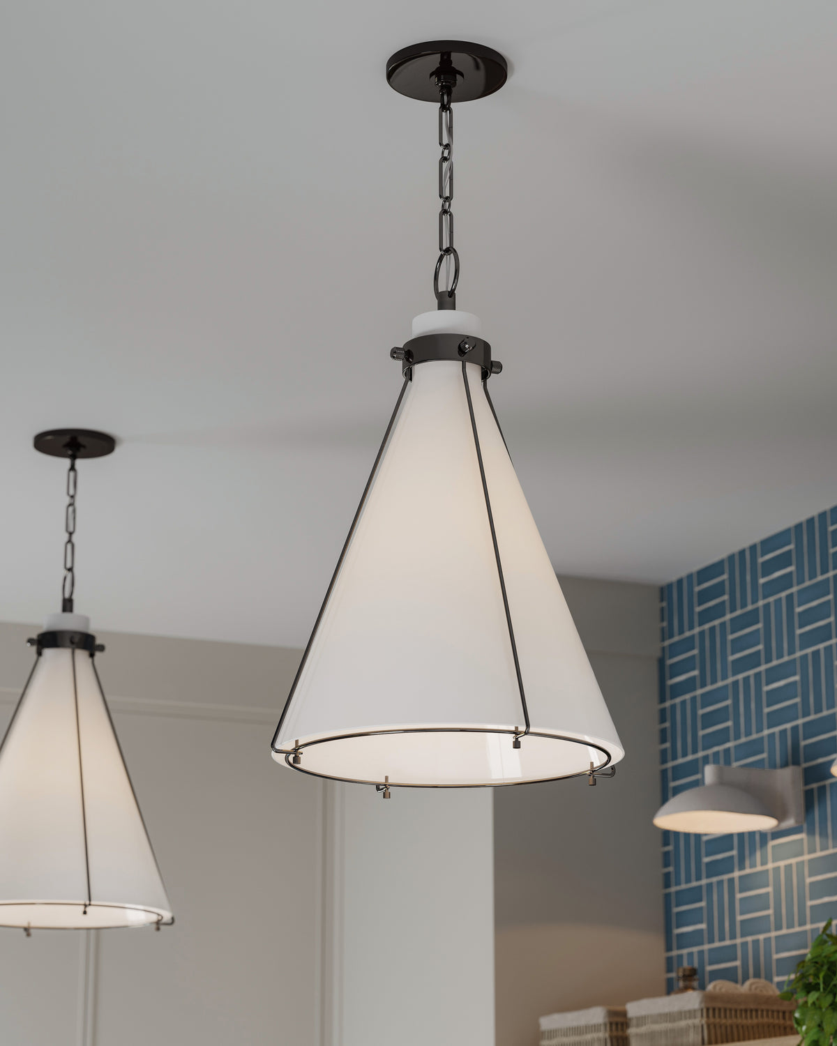 Modern cone pendant lights with frosted glass shades hanging above a kitchen island, complementing blue geometric tile backsplash.