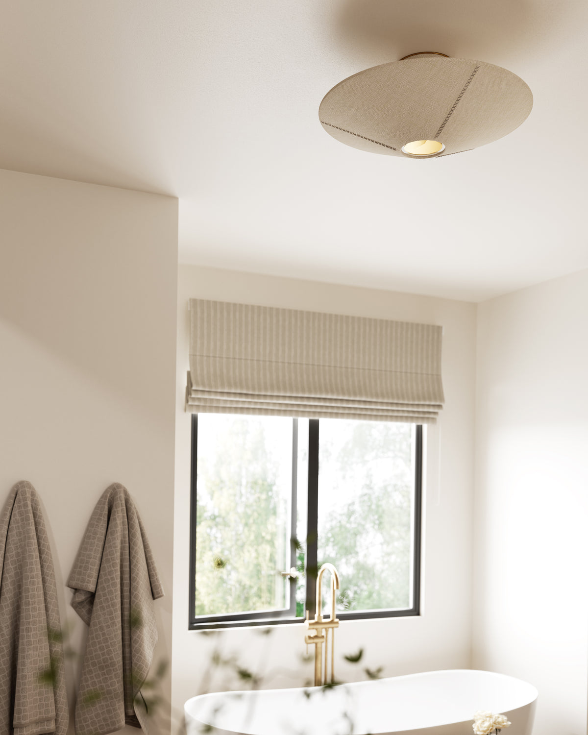 Flared semi-flush ceiling light in handwoven natural fiber with gold leaf accents, casting warm light over a serene bathroom with tub and window