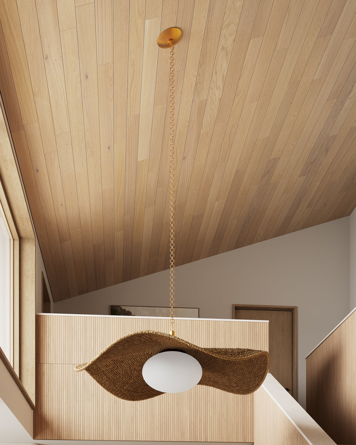 Leaf-shaped woven chandelier with frosted glass diffuser suspended from a gold chain above a modern wood interior with vaulted ceiling.