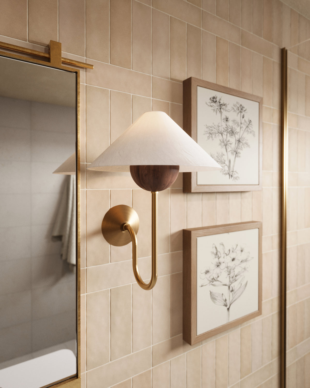 Patina brass wall sconce with J-shaped arm, walnut bobeche, and tapered white linen shade mounted on beige tile beside mirror and framed art