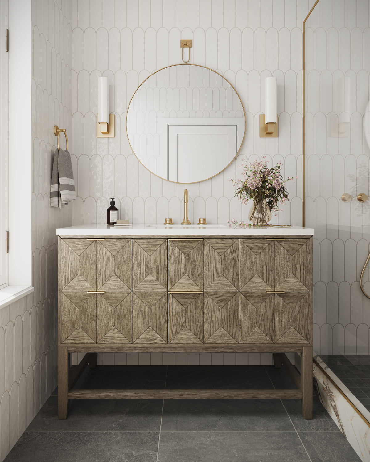Elegant Gwen 48" vanity in pebble oak with diamond-patterned drawers and brass hardware styled with a large round mirror, set against  white fish scale wall tiles.