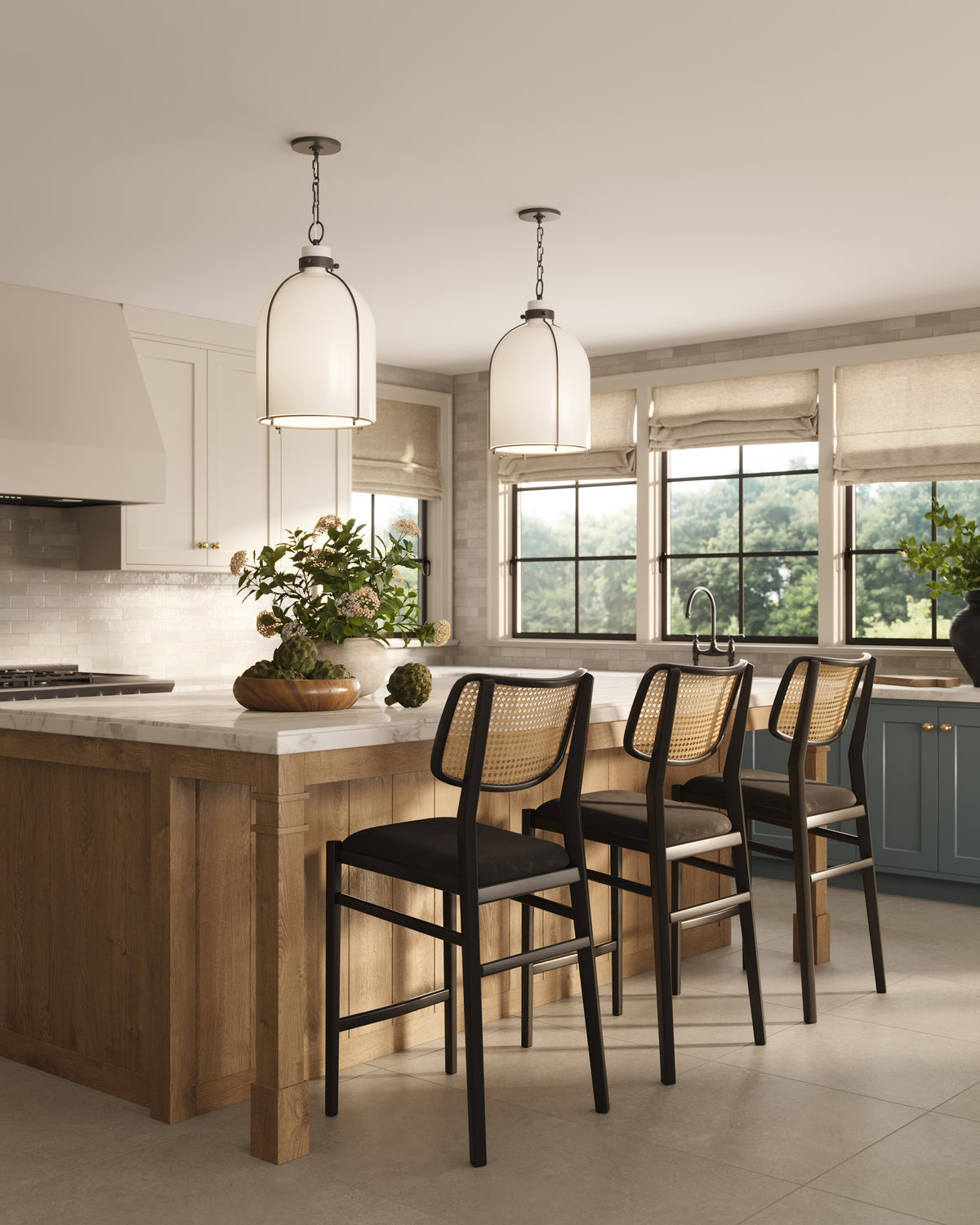 Bright kitchen with marble island, woven bar stools, and two old bronze dome pendant lights illuminating the seating area.