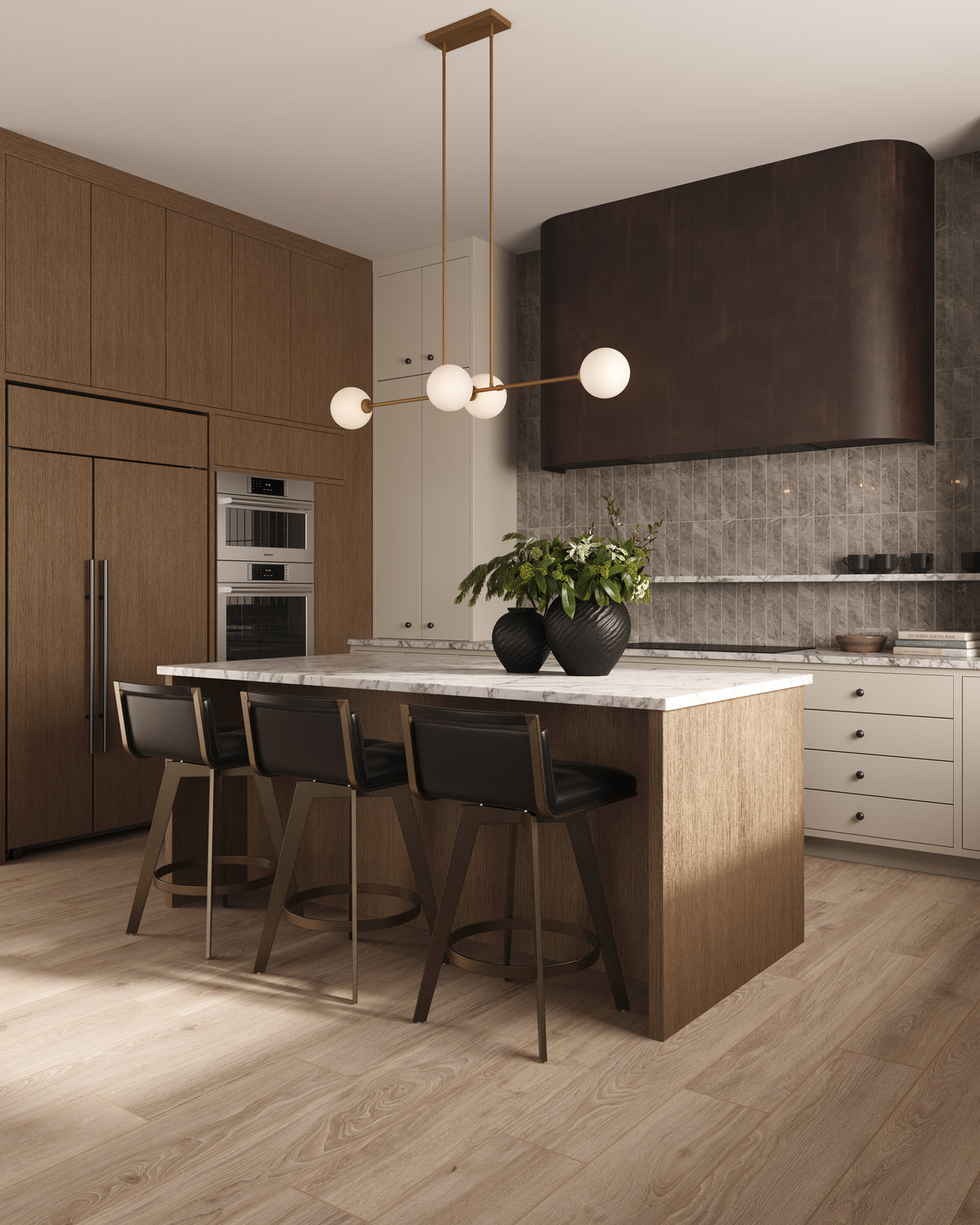 Modern kitchen with wood cabinetry, subway tile wall, wood look flooring, marble island, black bar stools, and brass linear pendant light with globe shades.