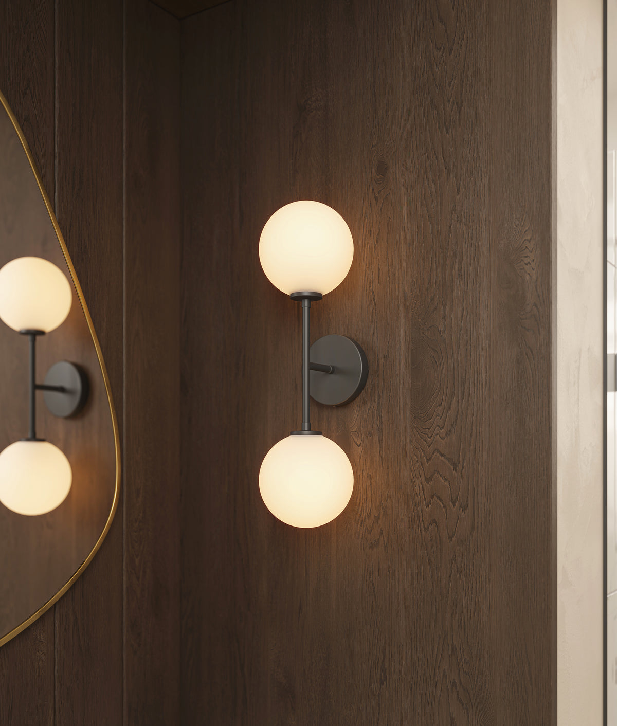 Bathroom wall sconce with dual frosted glass globe shades and matte black arm mounted on a dark wood panel wall.