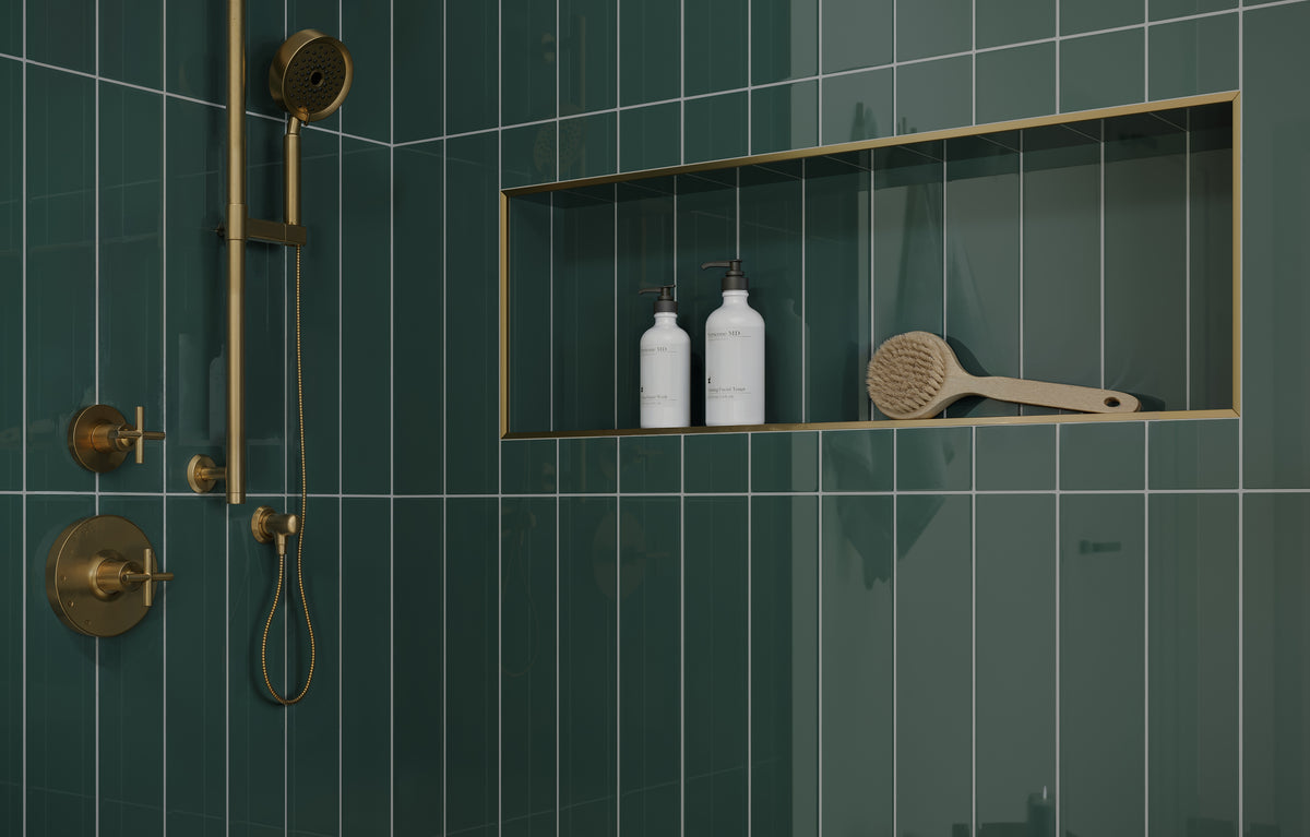 Jaxson 4x21 glossy ceramic tile in Pine, showcasing forest green tones in a sleek vertical layout, accented by gold trim and fixtures.