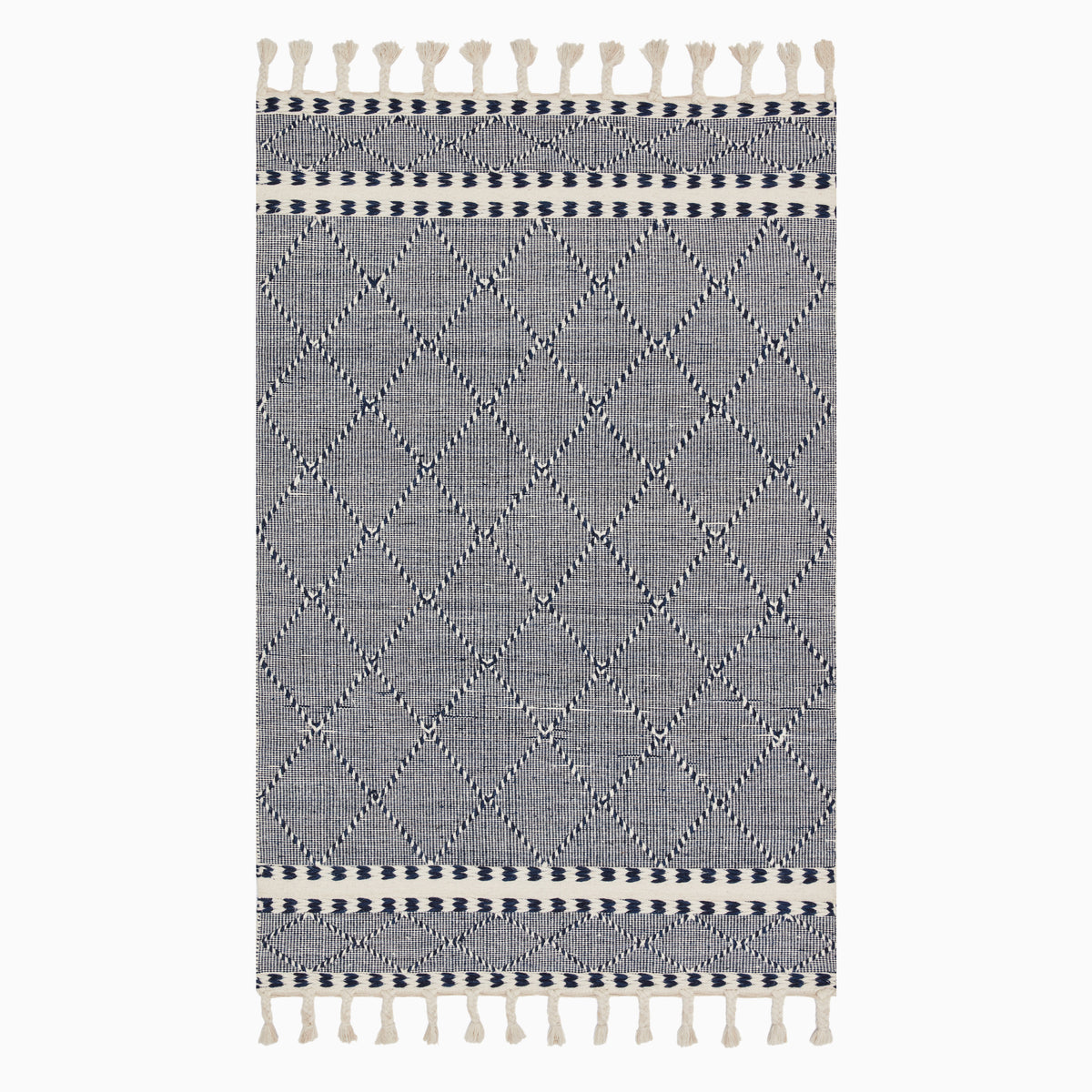 Boho-inspired hand loomed wool area rug with a navy and white geometric diamond pattern and tassel fringe, blending style and texture.