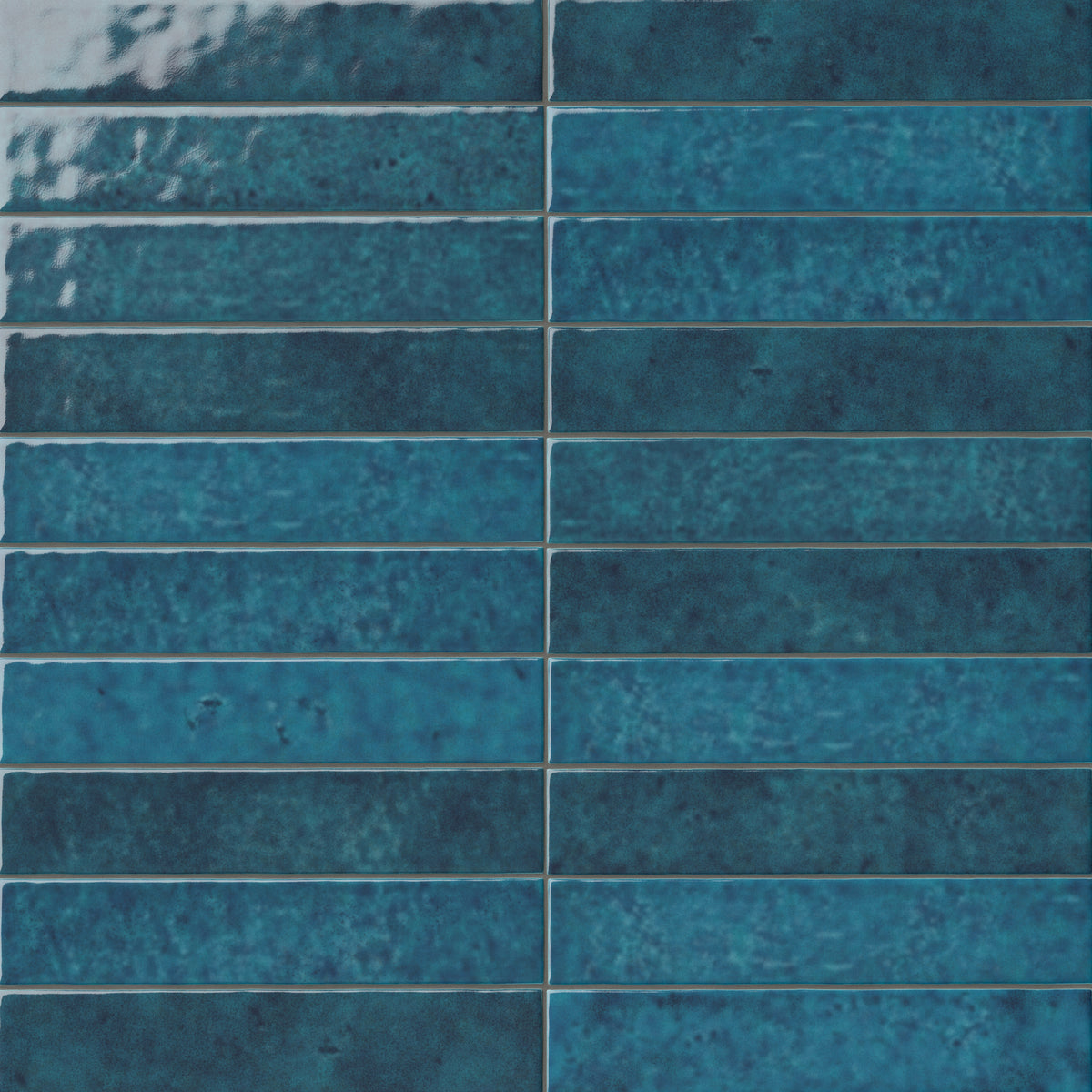 Blue 2x13 ceramic wall tiles arranged in a linear layout, showcasing layered ocean-inspired tones, subtle movement in the glaze, and artisanal character throughout the installation.