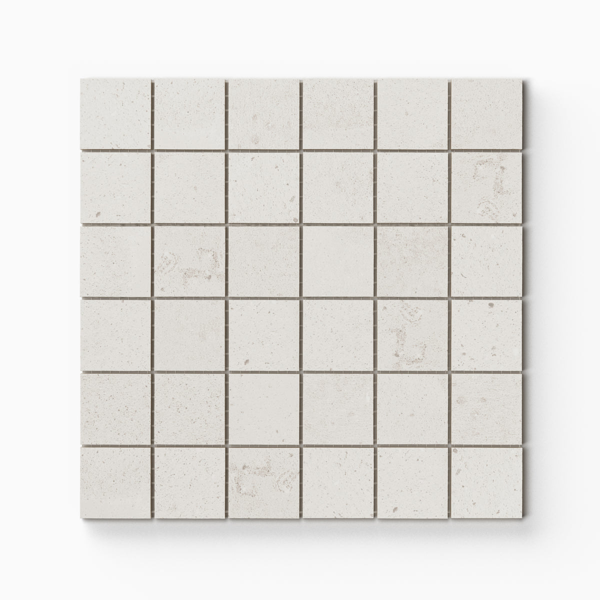 Off-white matte porcelain mosaic tile in a mesh-mounted square format, featuring visual mineral flecks inspired by the shifting texture of Italian Riviera sand.