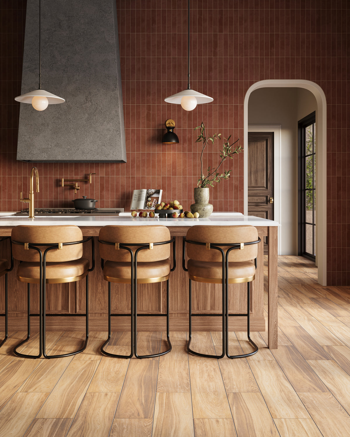 Modern rustic kitchen with terracotta subway tile walls, golden brown wood look plank tile flooring, oak island with bar stools, pendant lights, and sculptural hood.
