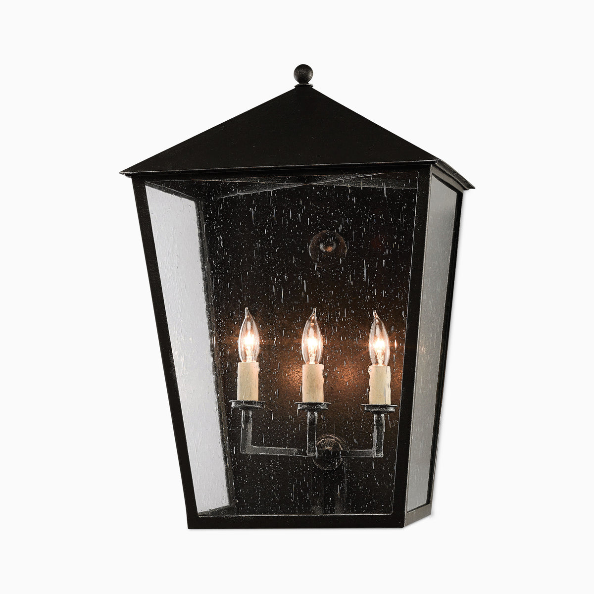 Classic black outdoor lantern-style wall sconce in large size, with seeded glass panels, three candle-style bulbs, and pitched top.