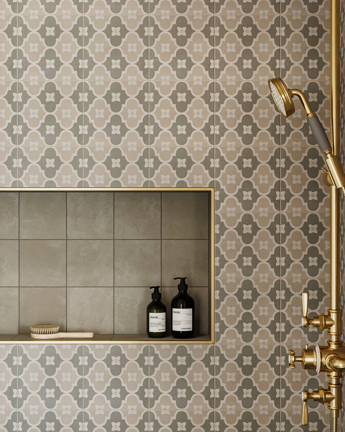 This shower features gray porcelain tiles with subtle patterning, bringing gentle depth and rhythm to the wall while pairing easily with brass hardware and built-in niches.