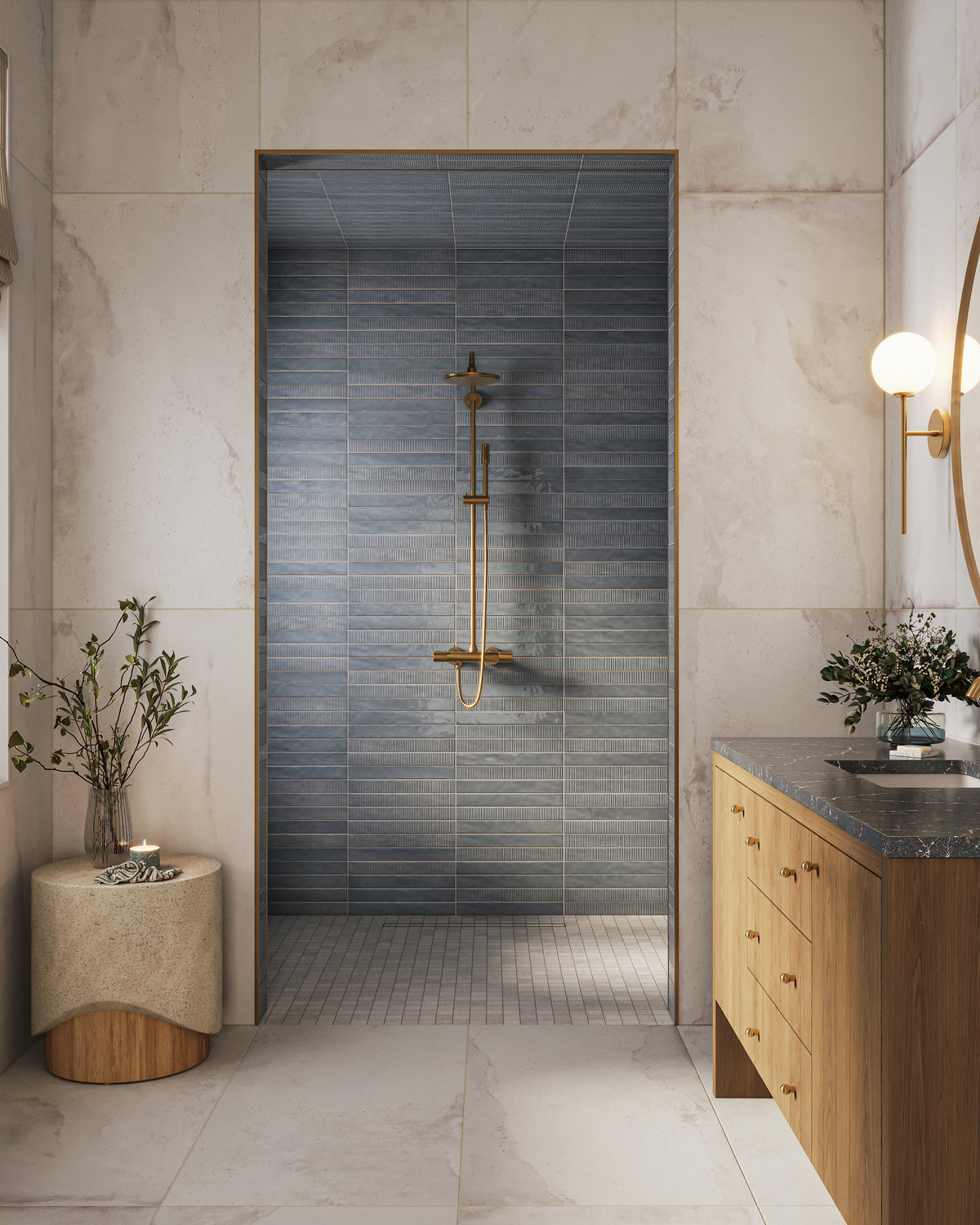 Bathroom with a walk-in shower framed by large marble-look wall tile, featuring blue stacked subway wall tile inside the shower, off-white matte mosaic tile on the shower floor, brass fixtures, a wood vanity with a dark stone countertop, and a round wall sconce.