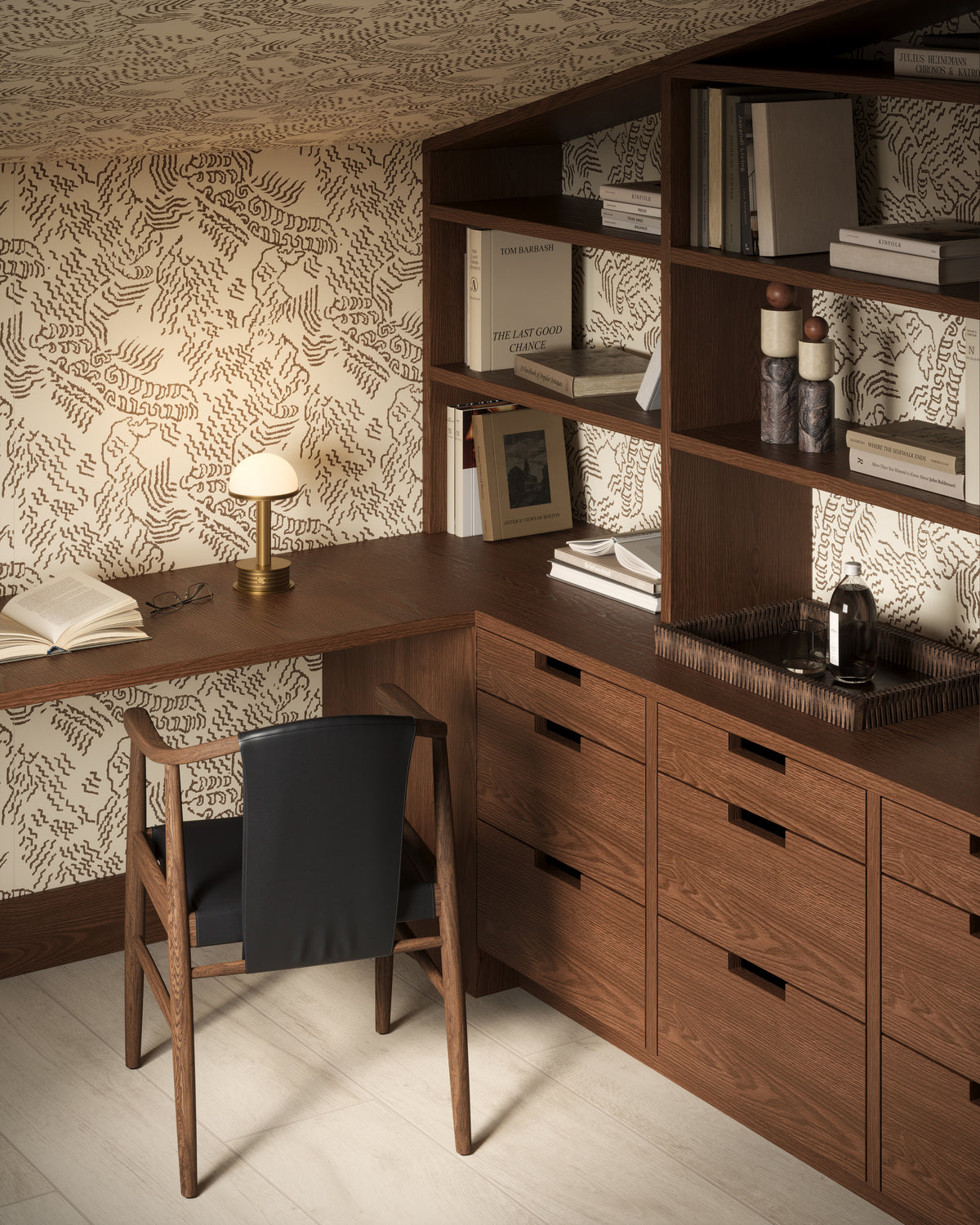 Moody modern home office with abstract wallpaper, warm wood built-ins, black chair, and glowing brass portable table lamp.