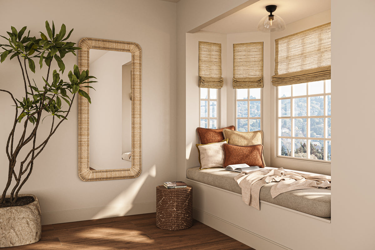 Clear glass dome semi flush mount light with a matte black base above a sunlit window seat with layered pillows, woven Roman shades, a rattan mirror, and a leafy indoor plant.
