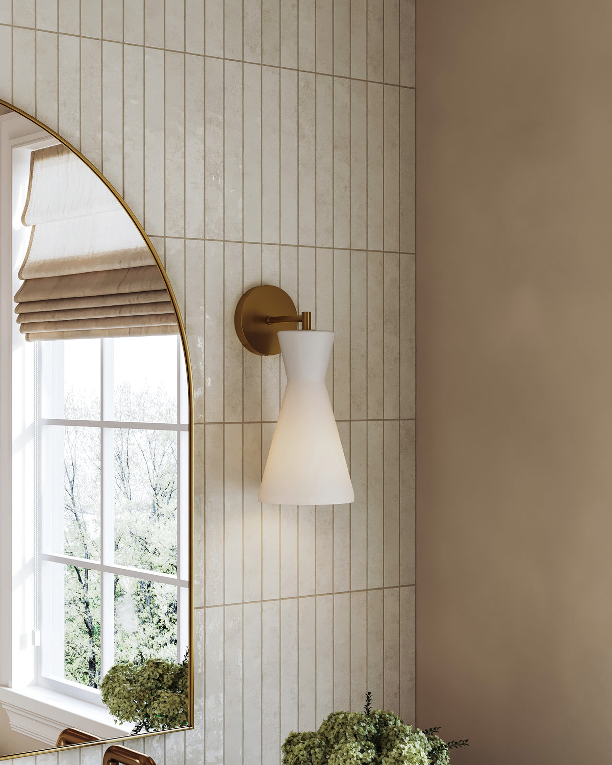 Modern bathroom with gold wall sconce and white glass shade, vertical beige subway tile backsplash, and arched mirror.